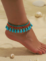 Colorful beaded anklet on a foot with sand and shells in the background