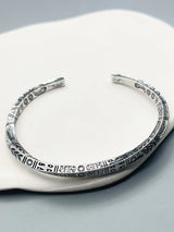 Silver bracelet with intricate patterns on a white surface