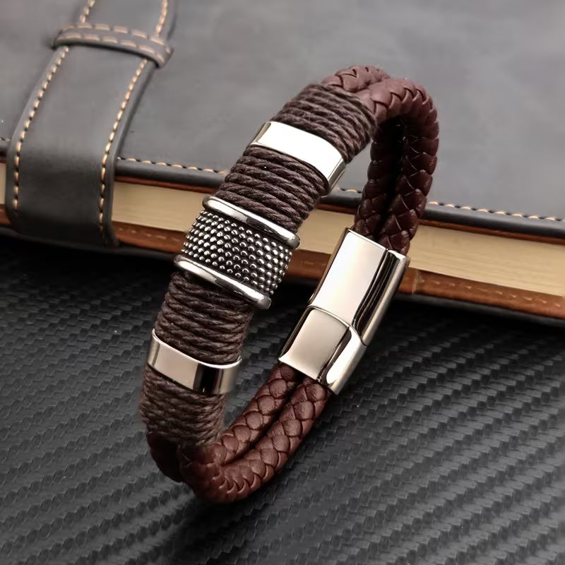 Brown braided bracelet with silver metal clasps on a textured surface