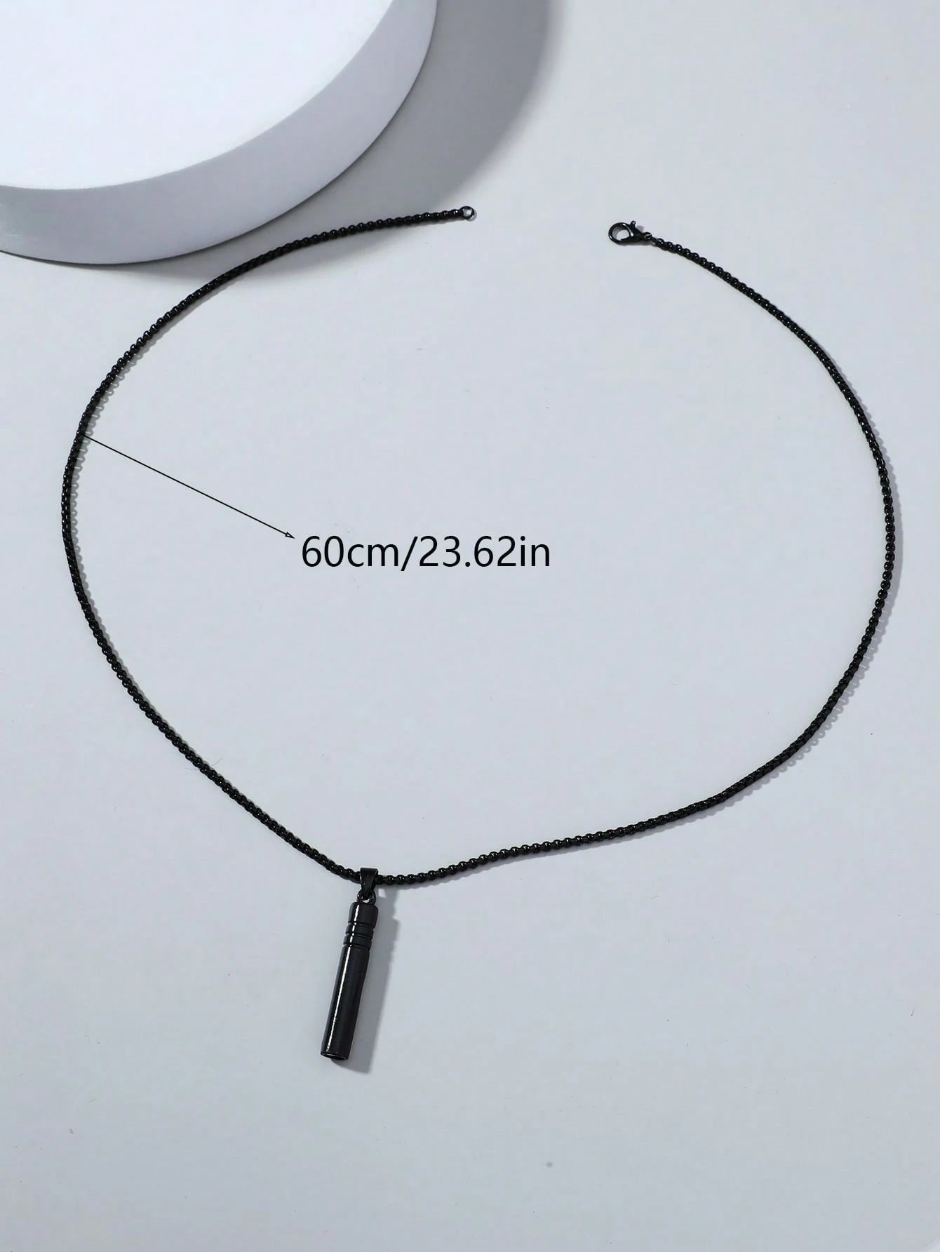 Black necklace with a pendant on a white background, showing measurement text.