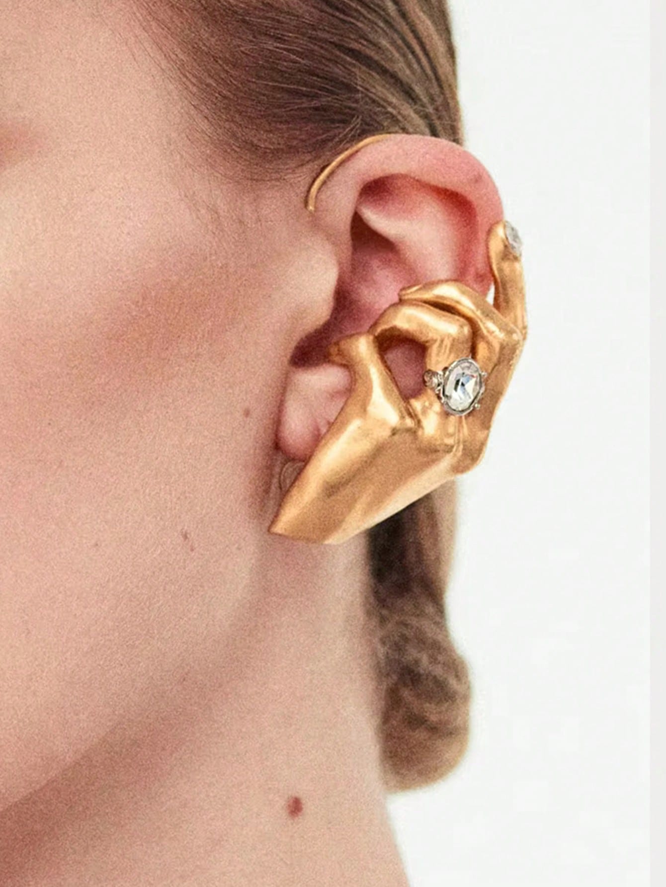 Gold ear cuff with a gemstone on a white background