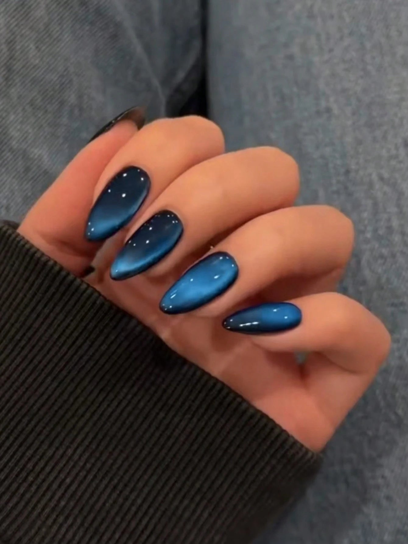 Hand with blue nail polish on a gray background