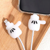 White silicone phone cable protectors shaped like cartoon hands, shown attached to a white charging cable near a smartphone on a wooden surface.