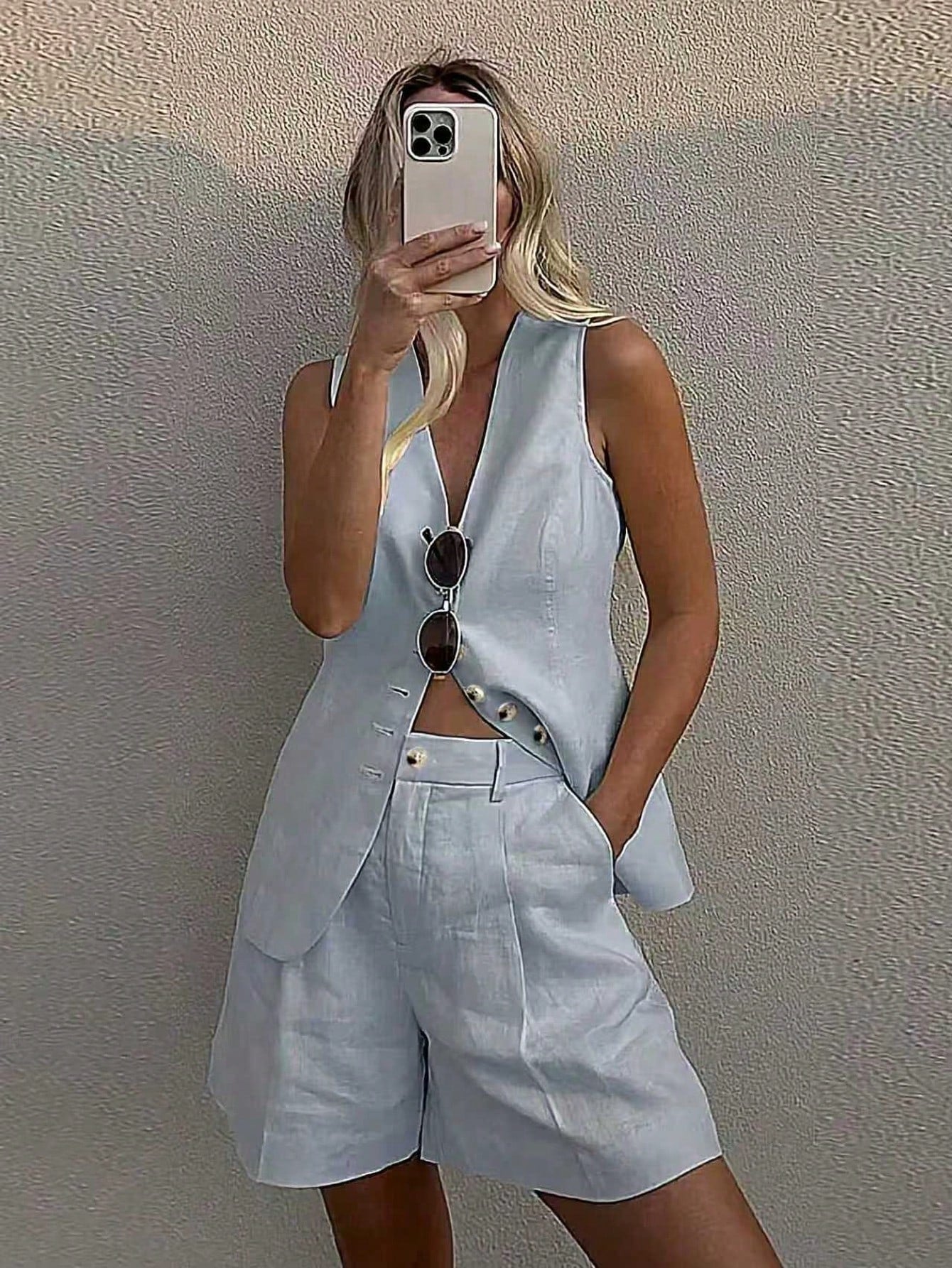 Person wearing a light blue outfit with shorts and a sleeveless top, standing against a plain background.