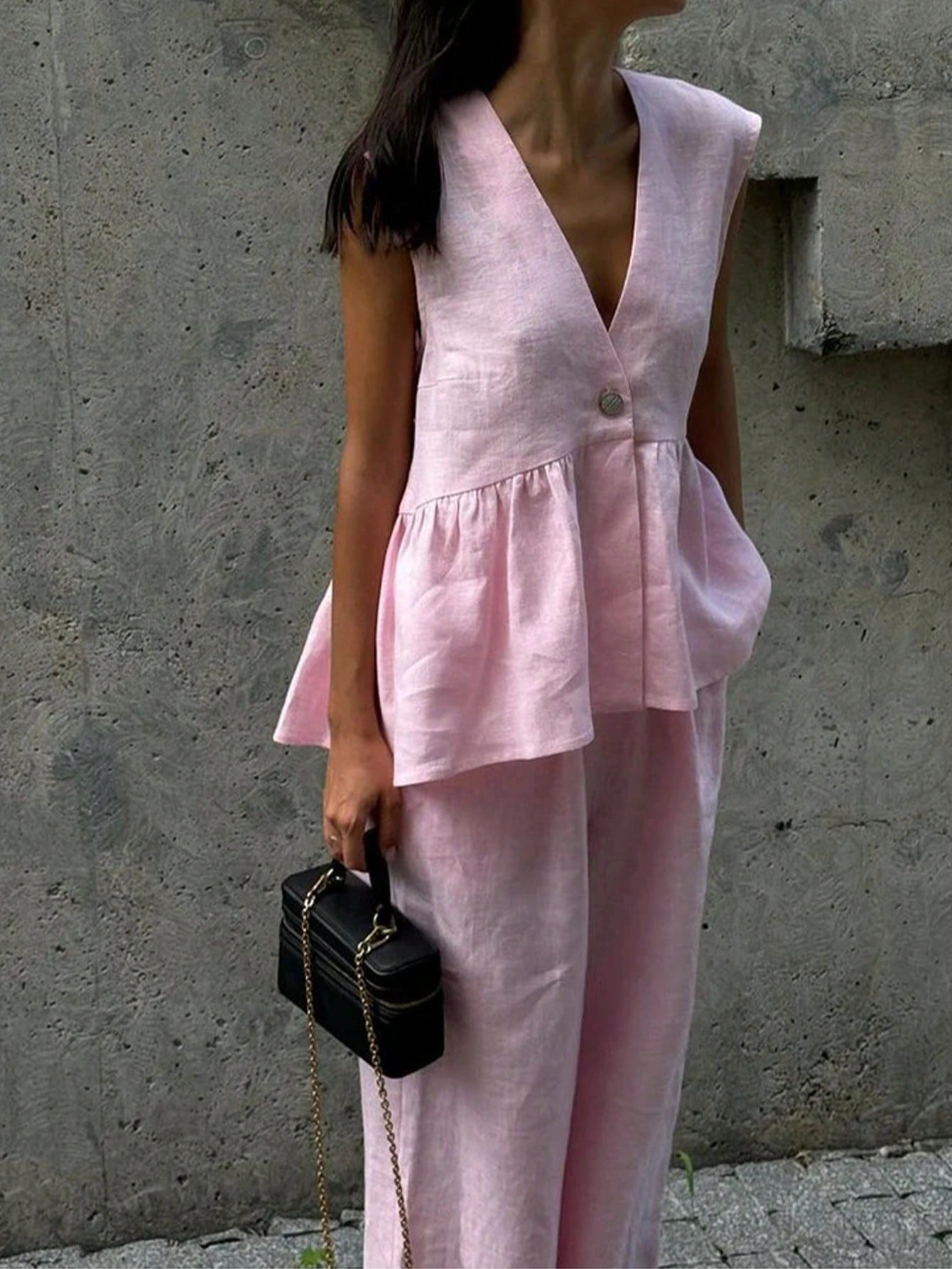 Woman wearing a light pink sleeveless top and pants against a beige background