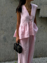 Woman wearing a light pink sleeveless top and pants against a beige background
