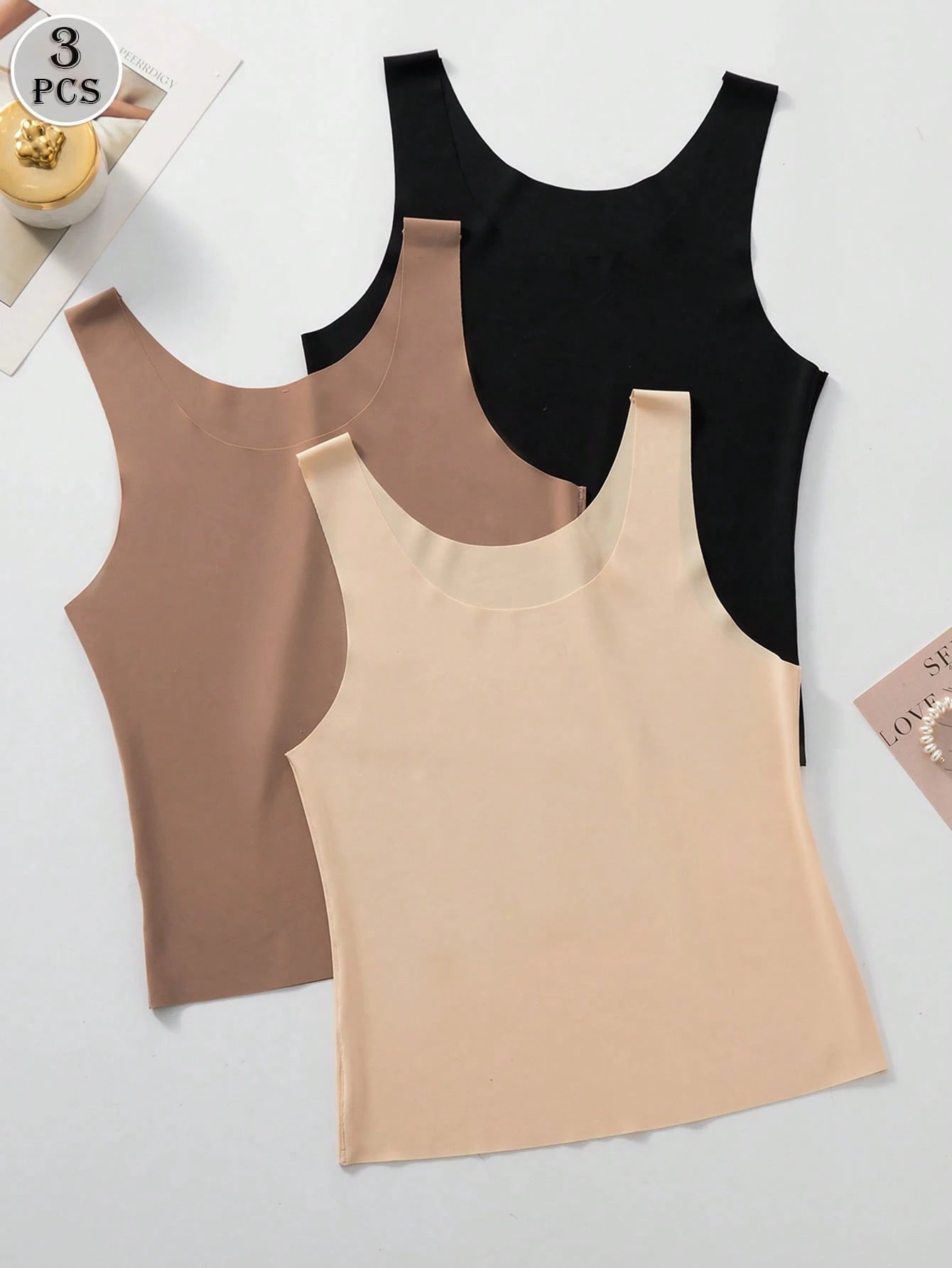 Three tank tops in black, beige, and brown on a light gray background