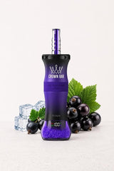 A purple and black Xvape disposable vape device with a metallic purple mouthpiece, styled on a light gray surface with blackcurrants, mint leaves, and ice cubes. The brand 'CROWN BAR' is clearly visible on the front of the device.