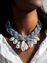 Necklace with braided design and large pearls worn by a person