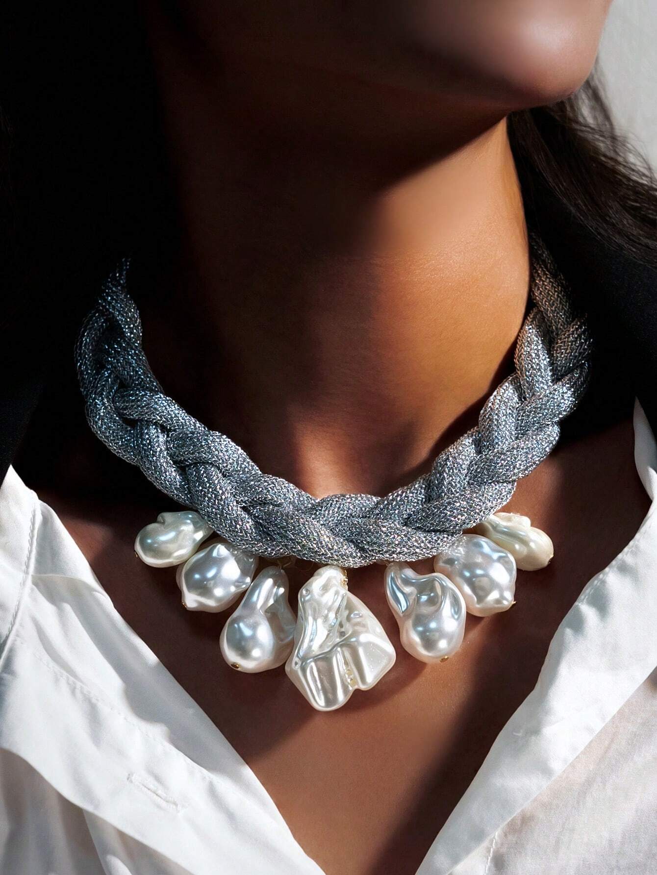 Necklace with braided design and large pearls worn by a person