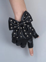 Black fingerless glove with a large bow and silver metallic studs, shown on a person's hand against a light gray background.