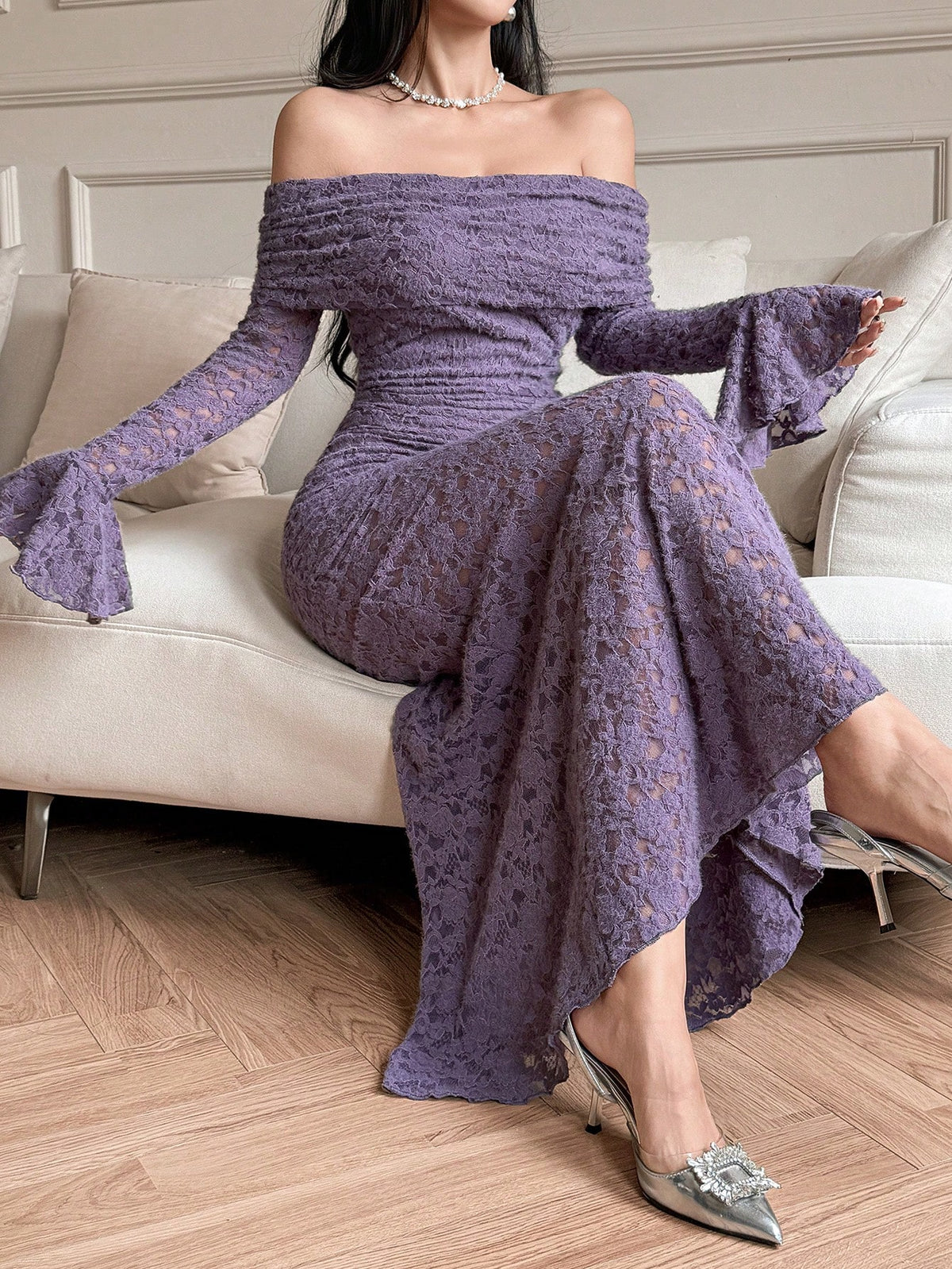 Woman wearing a purple off-shoulder dress sitting on a couch.