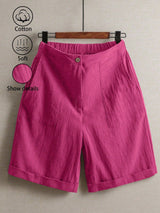 Pink shorts on a hanger with cotton and softness icons.