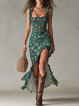 A woman models a green floral lace dress with a ruffled high-low hem and tie-shoulder straps, paired with brown cowboy boots and a woven straw bag against a neutral studio backdrop.