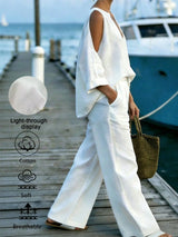 Person wearing a white outfit on a dock with a boat in the background