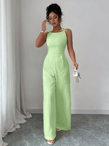 Woman wearing a light green jumpsuit standing against a plain background