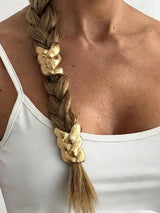 Person with braided hair adorned with gold hair accessories against a white background