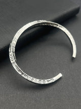 Silver bracelet with intricate patterns on a dark gray surface