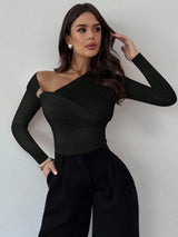 Woman wearing a brown one-shoulder top and black pants against a plain background