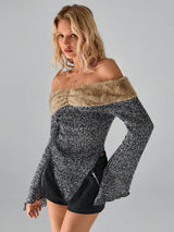 A woman modeling an off-the-shoulder long-sleeve knit top with a black and white marled body and a beige faux-fur collar, paired with black shorts, against a solid gray studio background.