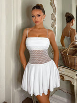 Woman wearing a white dress with a sheer overlay in a decorative room.