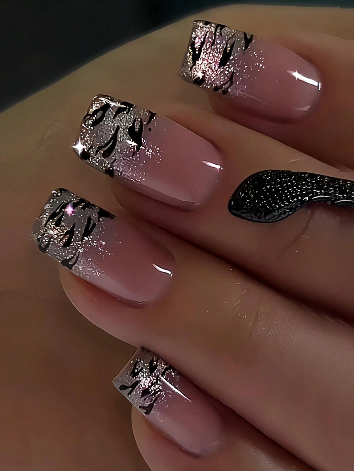 Nails with pink polish and silver decorative patterns on a neutral background