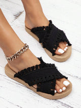 Black frayed sandals on a white wooden floor