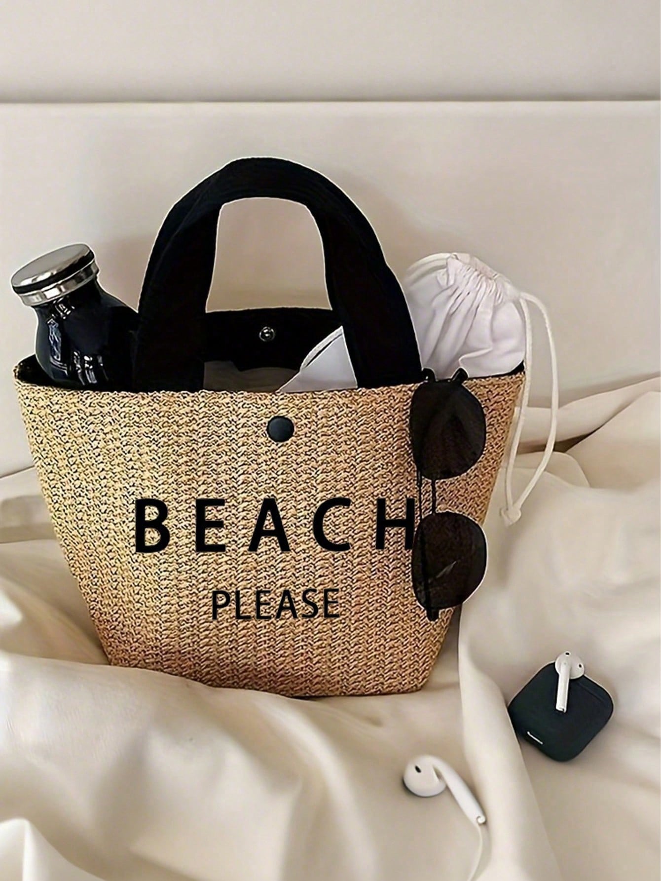 Woven bag with 'BEACH PLEASE' text on a white surface