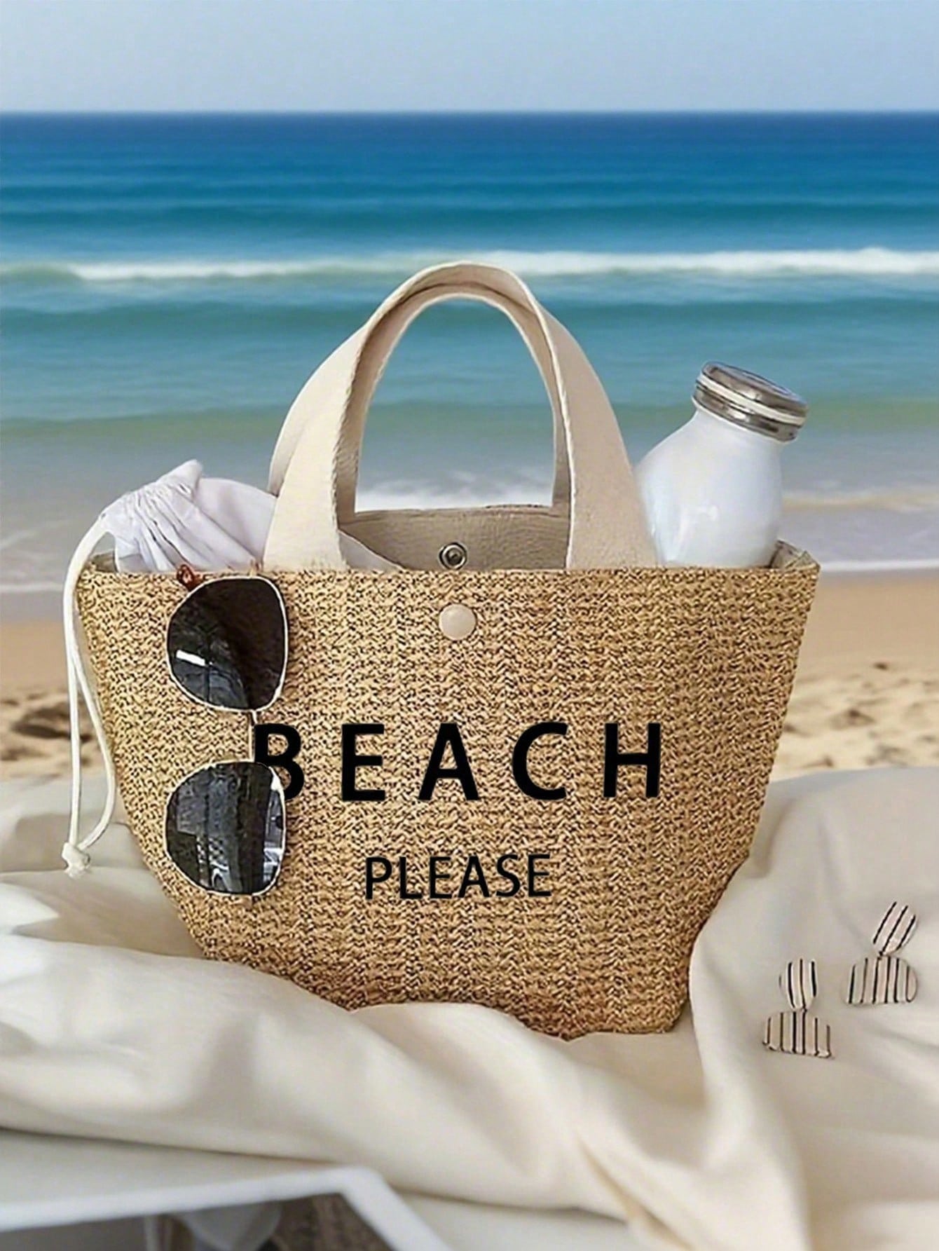 Beach bag with 'BEACH PLEASE' text on a sandy beach with ocean view