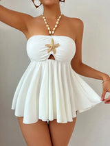 White strapless dress with starfish design and pearl necklace on a plain background