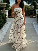 Woman in a strapless polka dot dress standing outdoors.