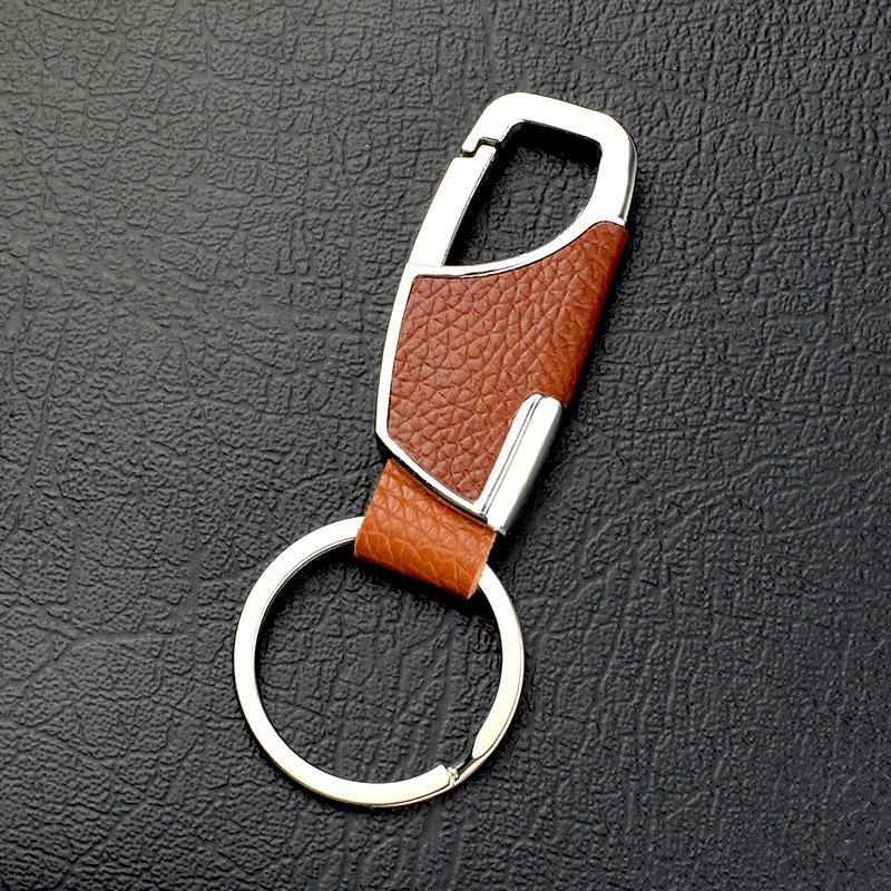 Brown leather keychain with silver clip on a dark textured surface