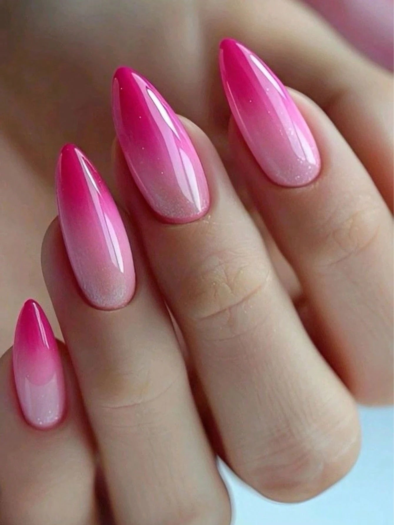 Hand with pink and red gradient nail polish on a light background