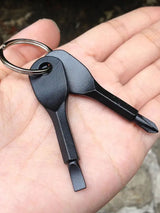 Multi-tool keychain with a keyring held in a hand against a blurred natural background