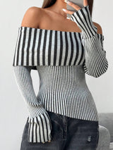 A woman wearing a black and white vertically striped off-the-shoulder long-sleeve knit top paired with dark gray jeans, shown in a close-up shot.