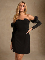 Woman wearing a black dress with arm sleeves against a beige background