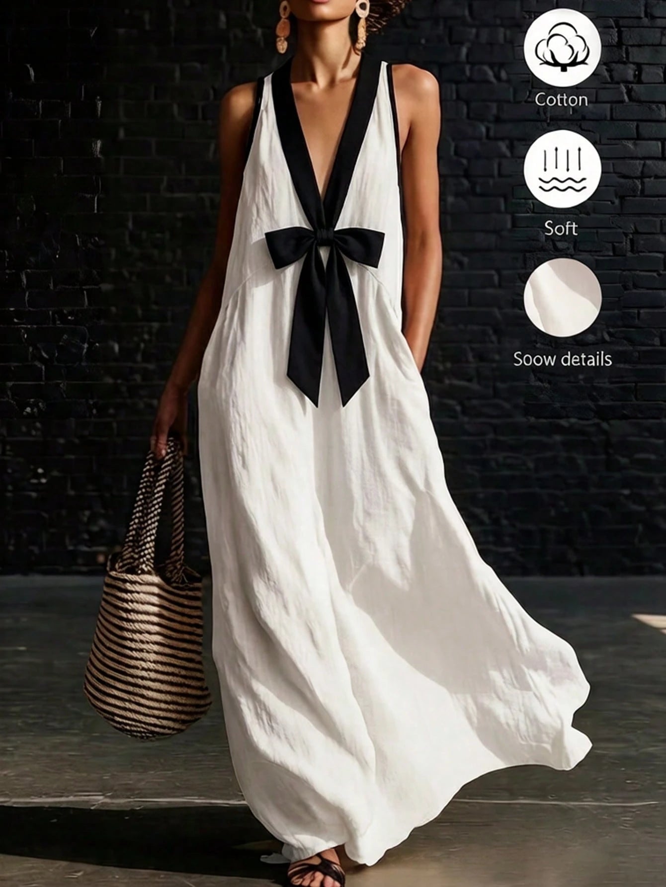 Woman wearing a white dress with a black bow, standing against a dark brick wall.