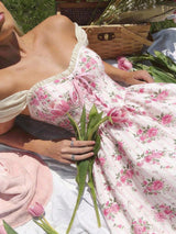 Woman in a floral dress holding tulips with a picnic basket in the background