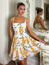 Woman wearing a white dress with lemon print in a decorative room.