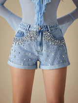 Denim shorts with rhinestone embellishments on a beige background