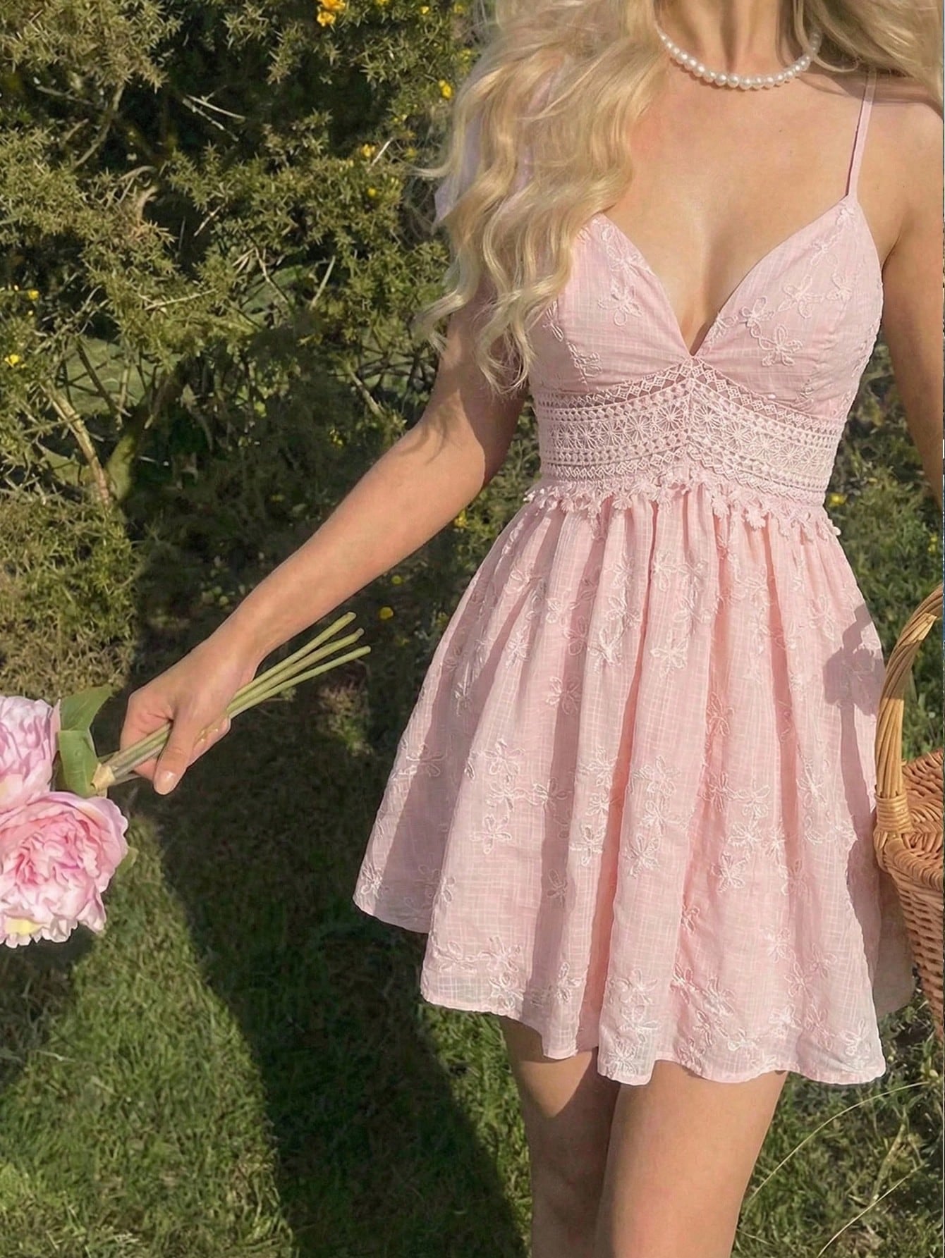 Woman in a pink lace dress holding flowers outdoors