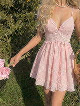 Woman in a pink lace dress holding flowers outdoors