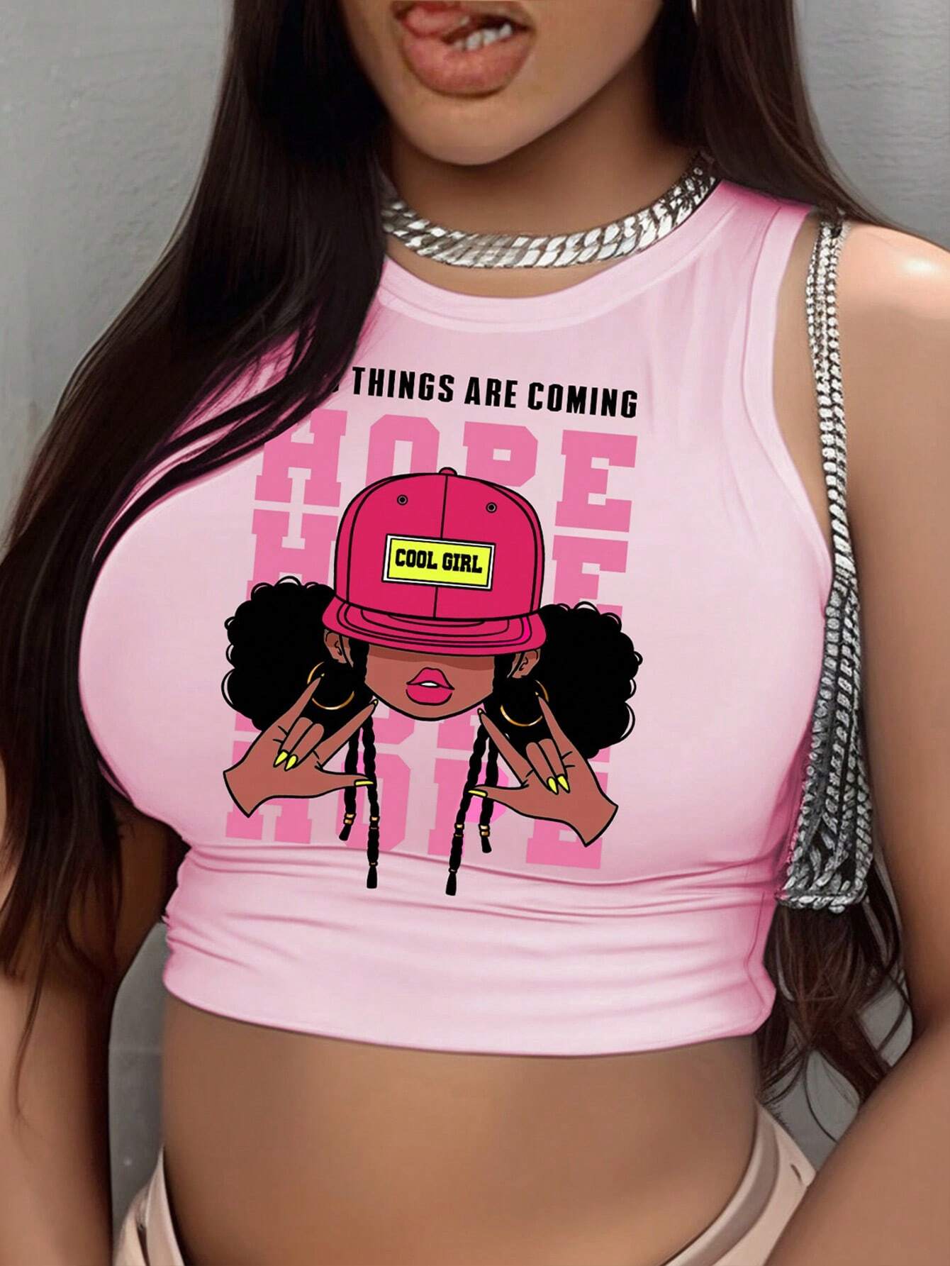 Pink crop top with graphic design and text, worn by a person.