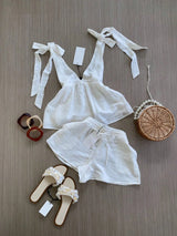 White lace top and shorts with accessories on a wooden surface