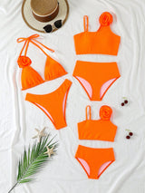 Orange bikini set with matching top and bottom on a white surface with decorative items.