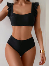 Black bikini with ruffled straps worn by a person on a plain background