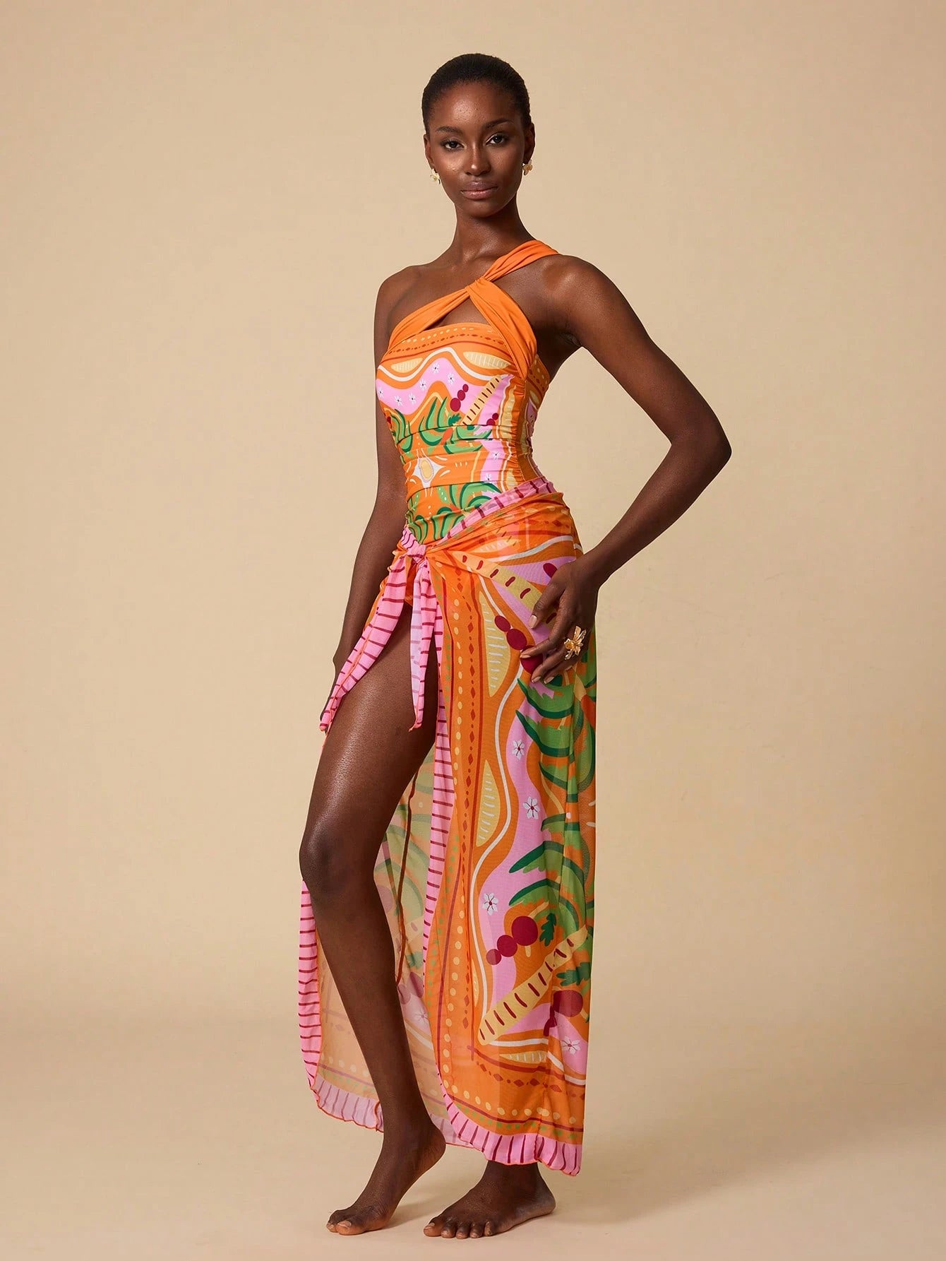 Woman wearing a colorful one-shoulder dress with floral patterns on a beige background