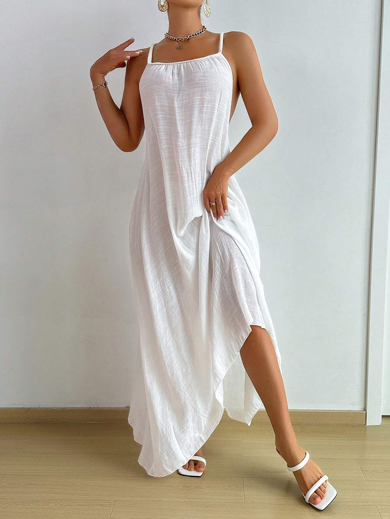 Woman wearing a white sleeveless dress against a plain background