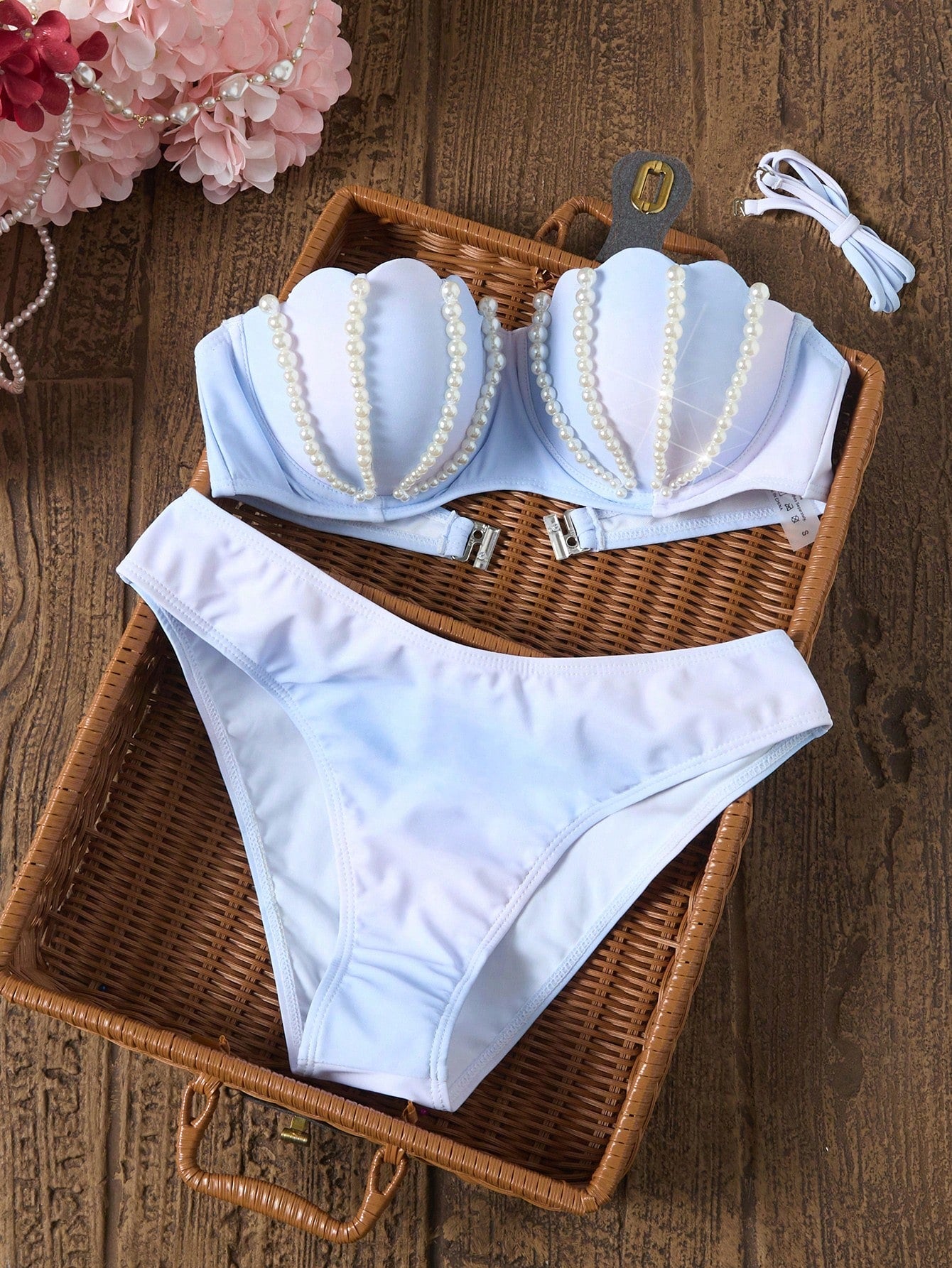 Light blue bra and panties set with pearl details on a wicker tray.