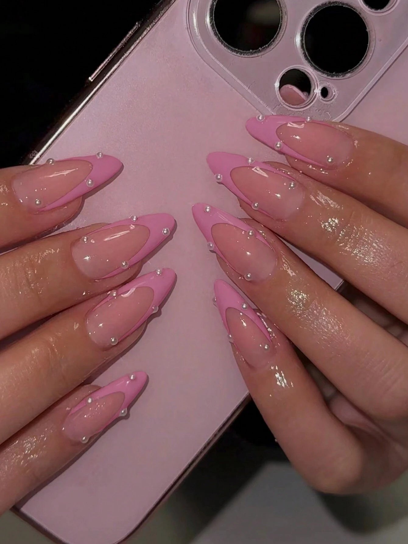 Close-up of hands with pink nail polish holding a pink phone case.